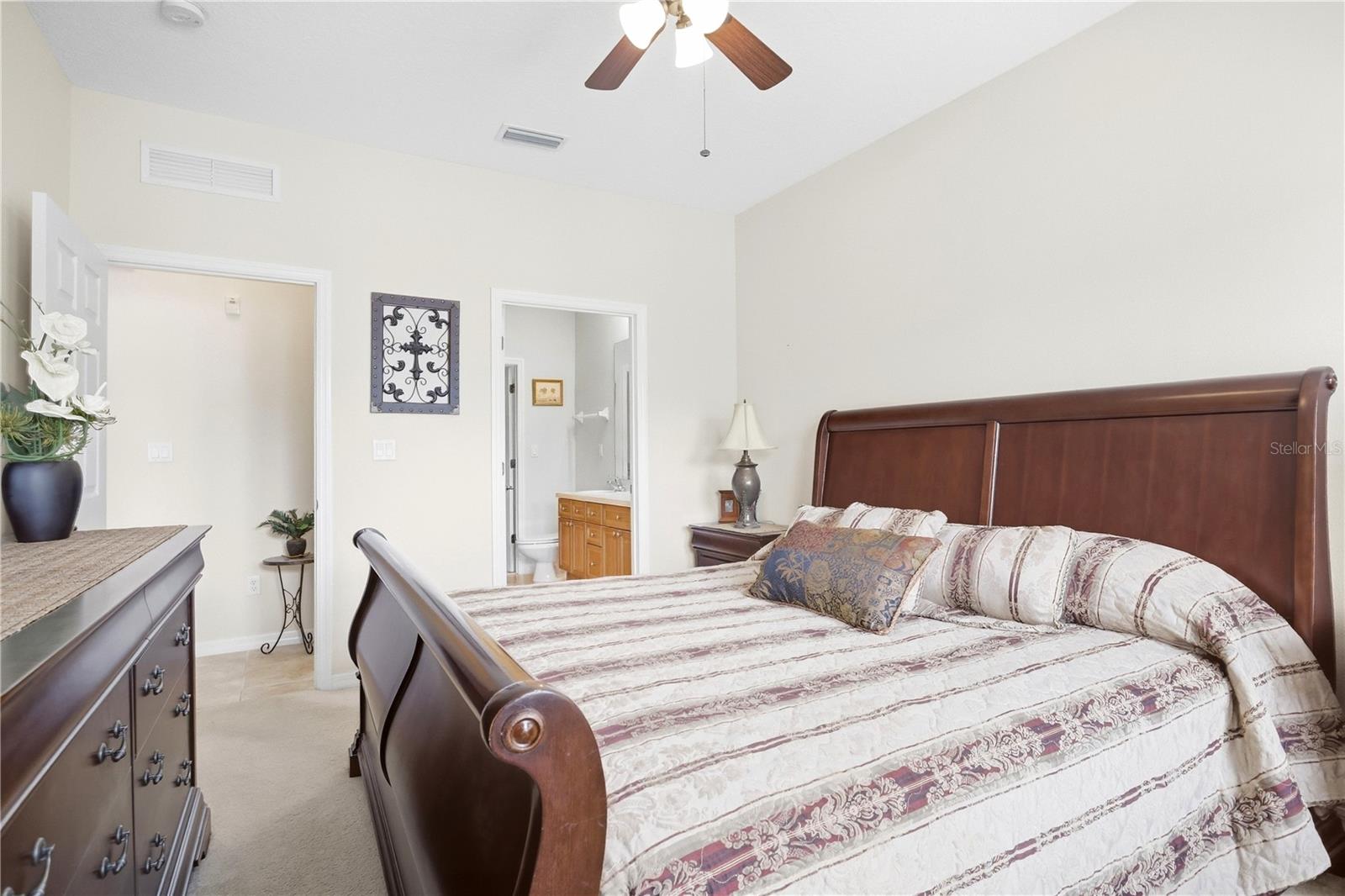 Bedroom with a dark wood sleigh bed, patterned bedding, and an open doorway to the ensuite bathroom.