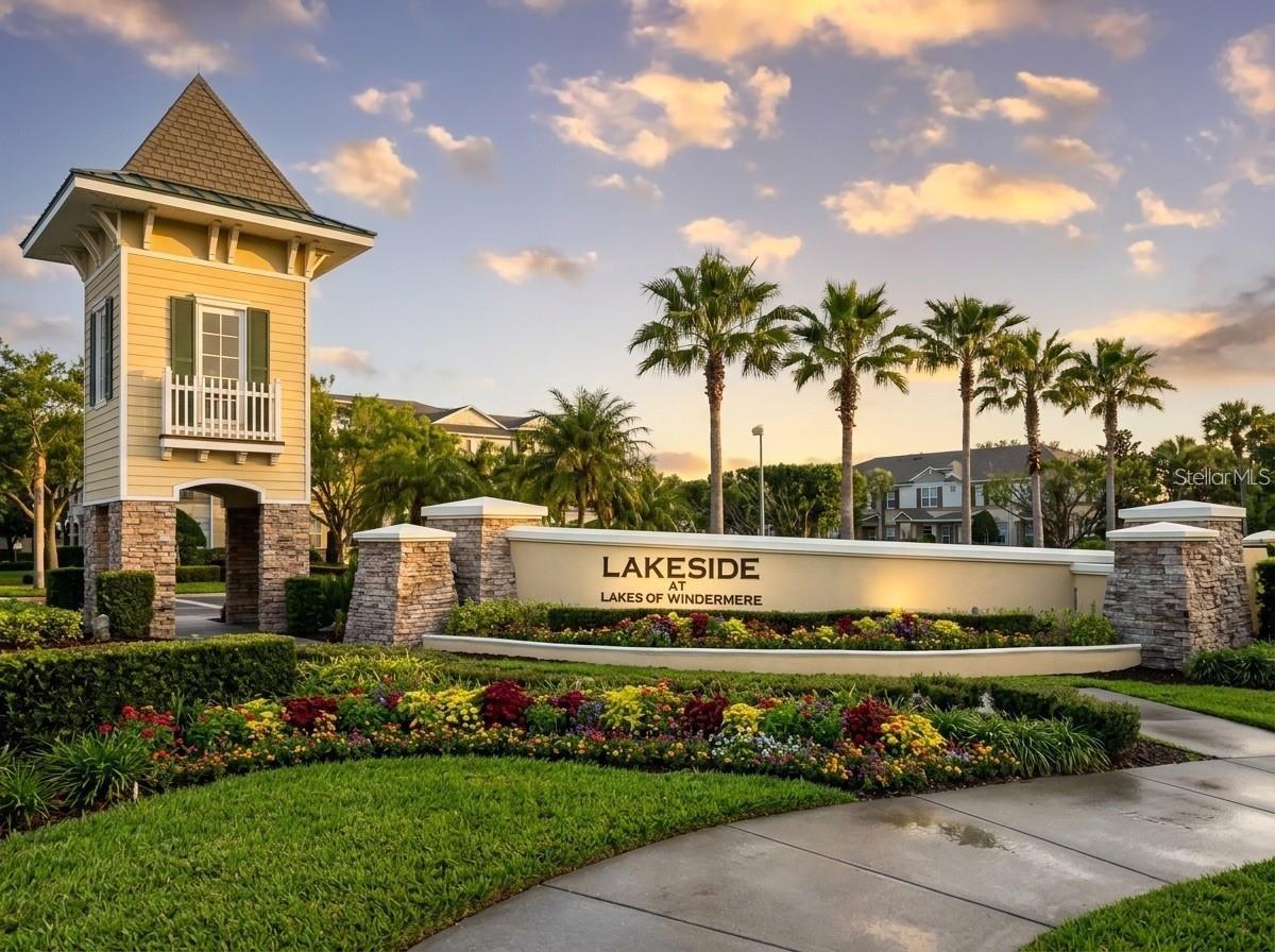 Lakeside at Lakes of Windermere entrance sign amid flower beds and palm trees.
