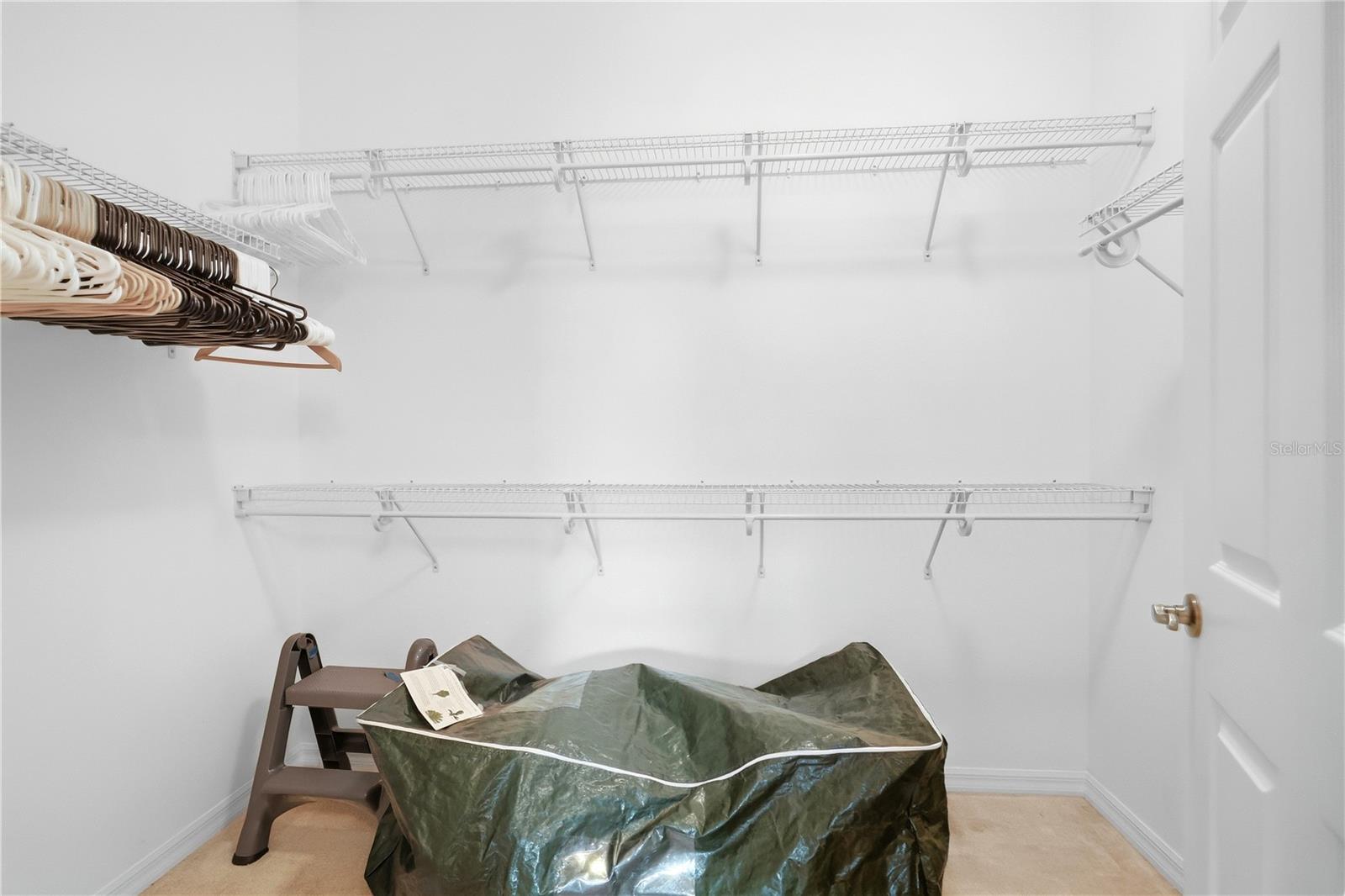 Walk-in closet with wire shelving, assorted hangers, and a covered item on the floor.