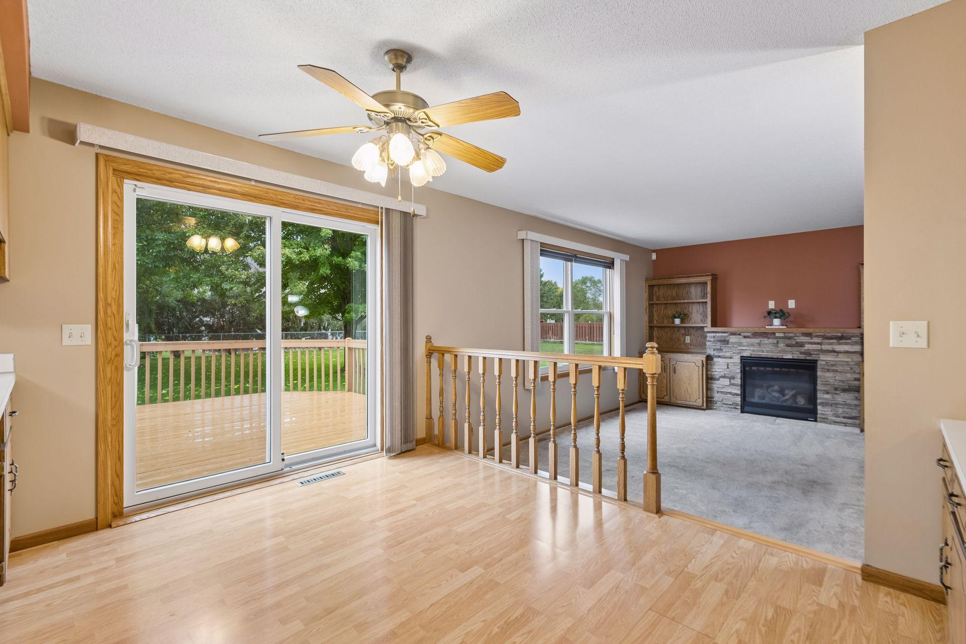 Open living area with a stone fireplace, wood flooring, and sliding doors to a deck.