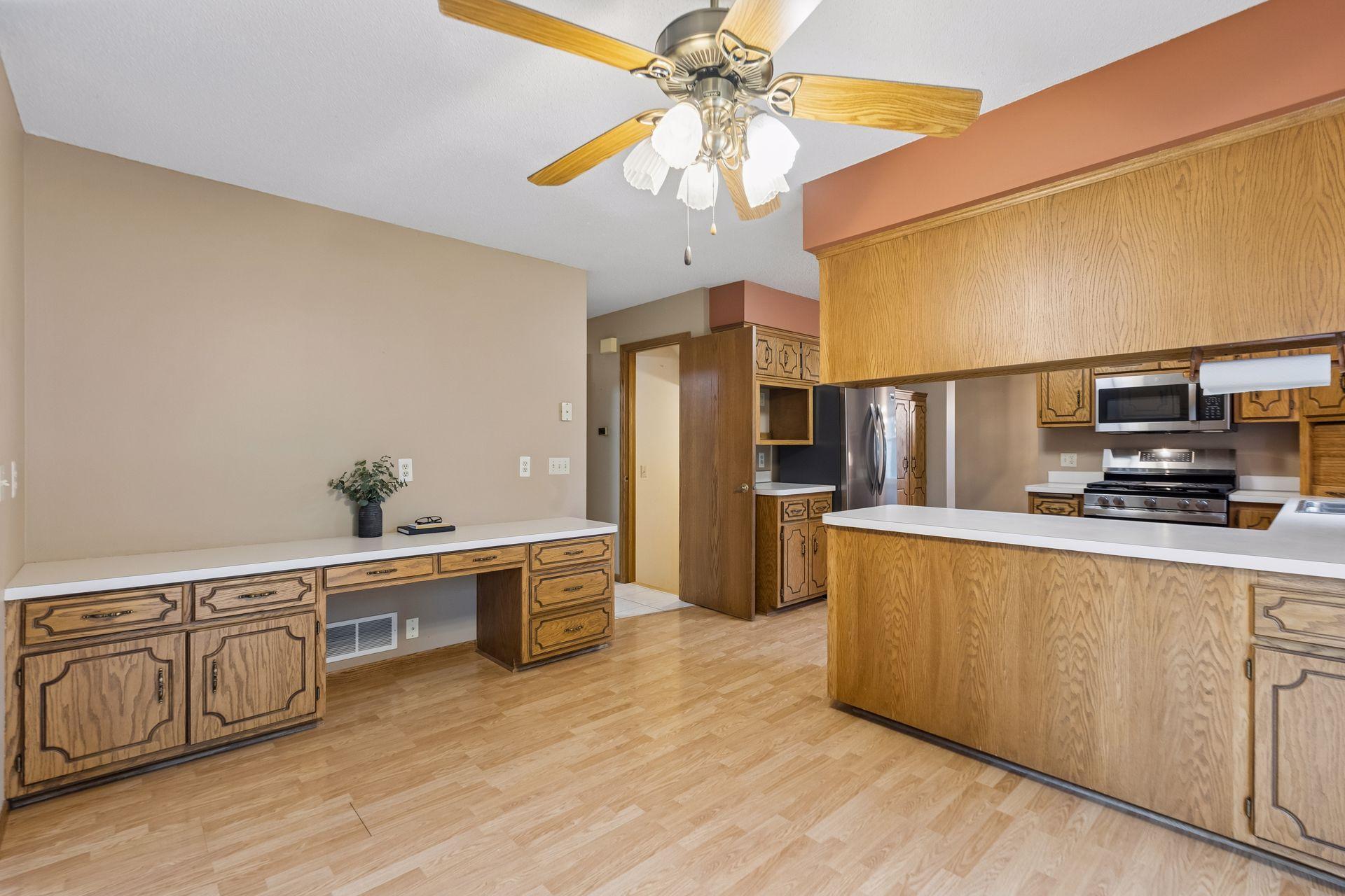 Kitchen with oak cabinetry, stainless steel appliances, and a built-in desk along the wall.