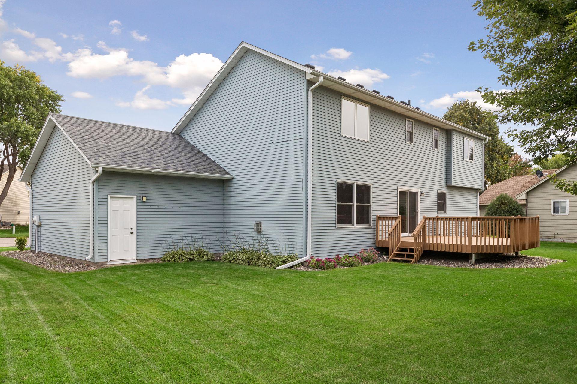 Two-story home with a raised wooden deck and broad green lawn at the rear.