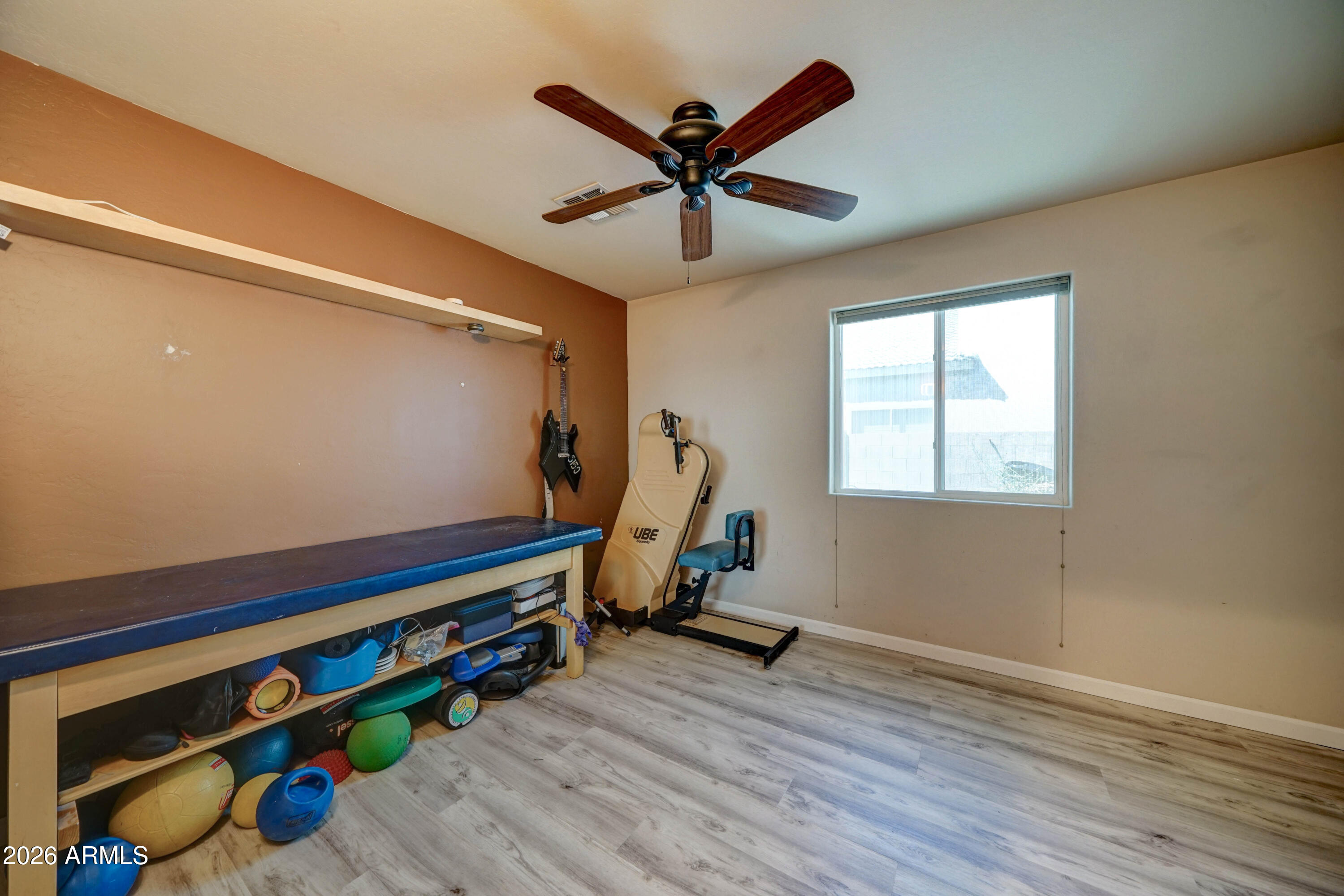 Exercise room with workout equipment, a padded table, guitars, and a window.