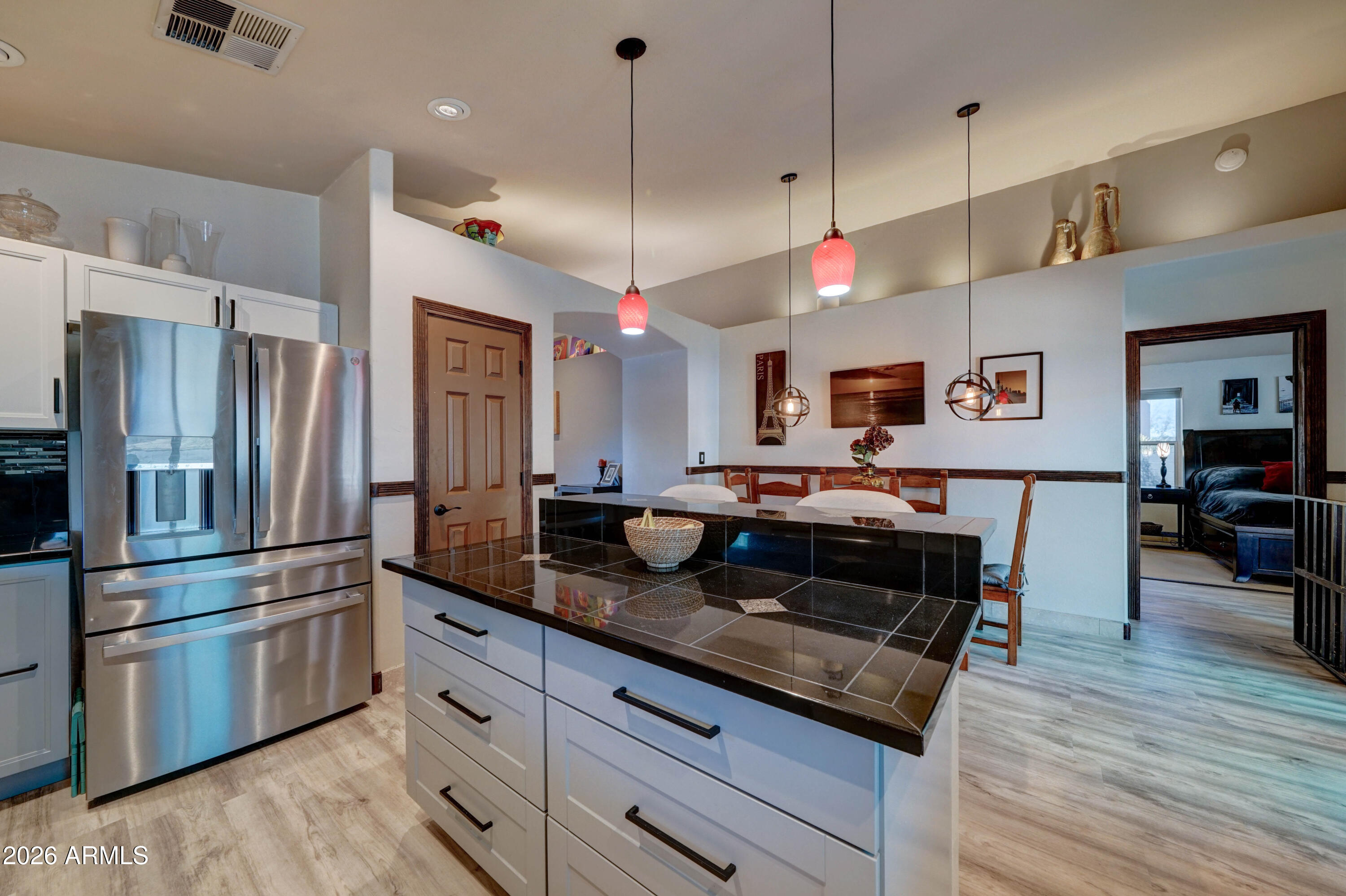 Kitchen with a large black-tiled island, stainless steel refrigerator, and adjoining dining area.