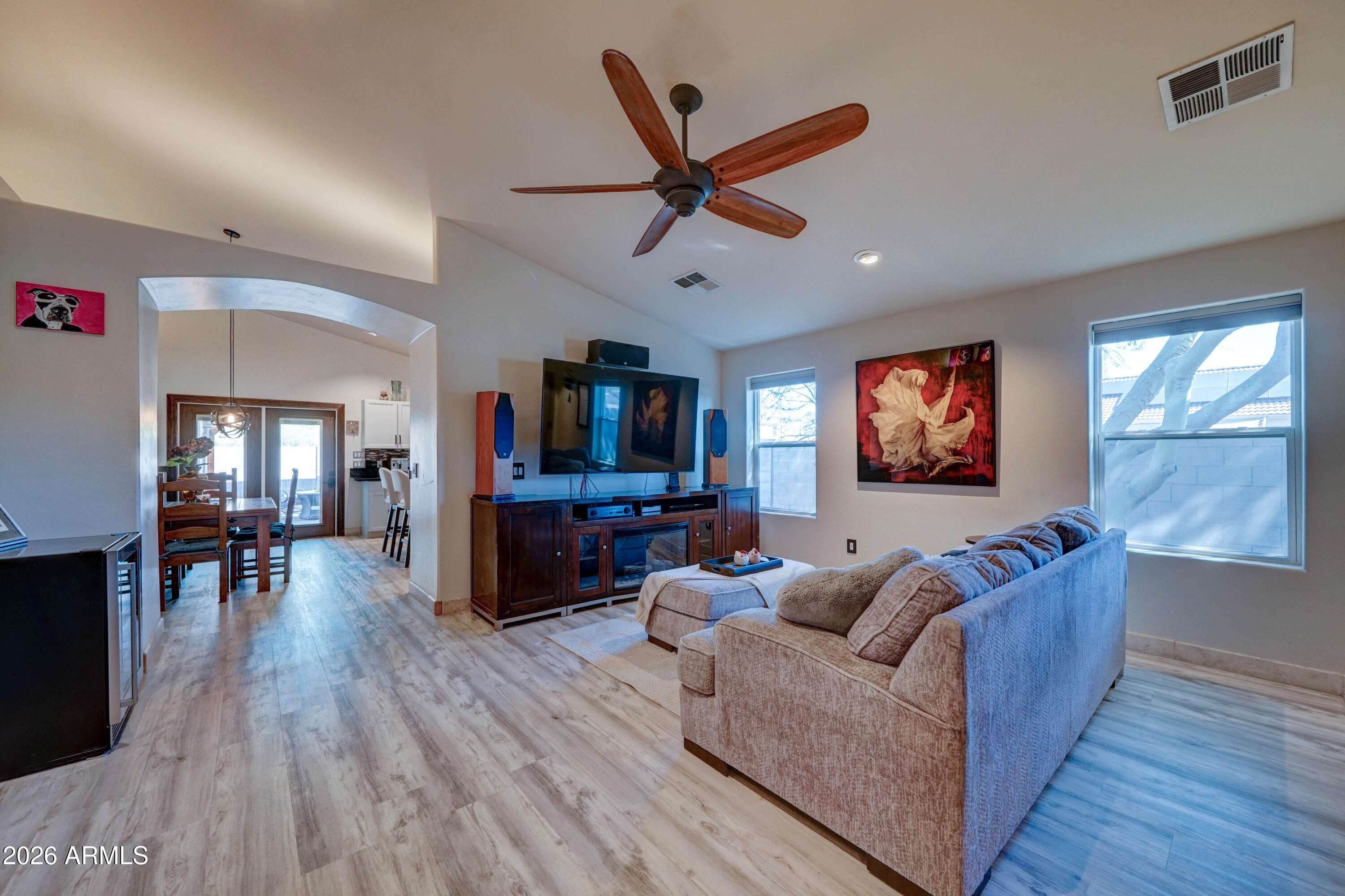 Living room with a large sectional, wood-blade ceiling fan, and open dining area.