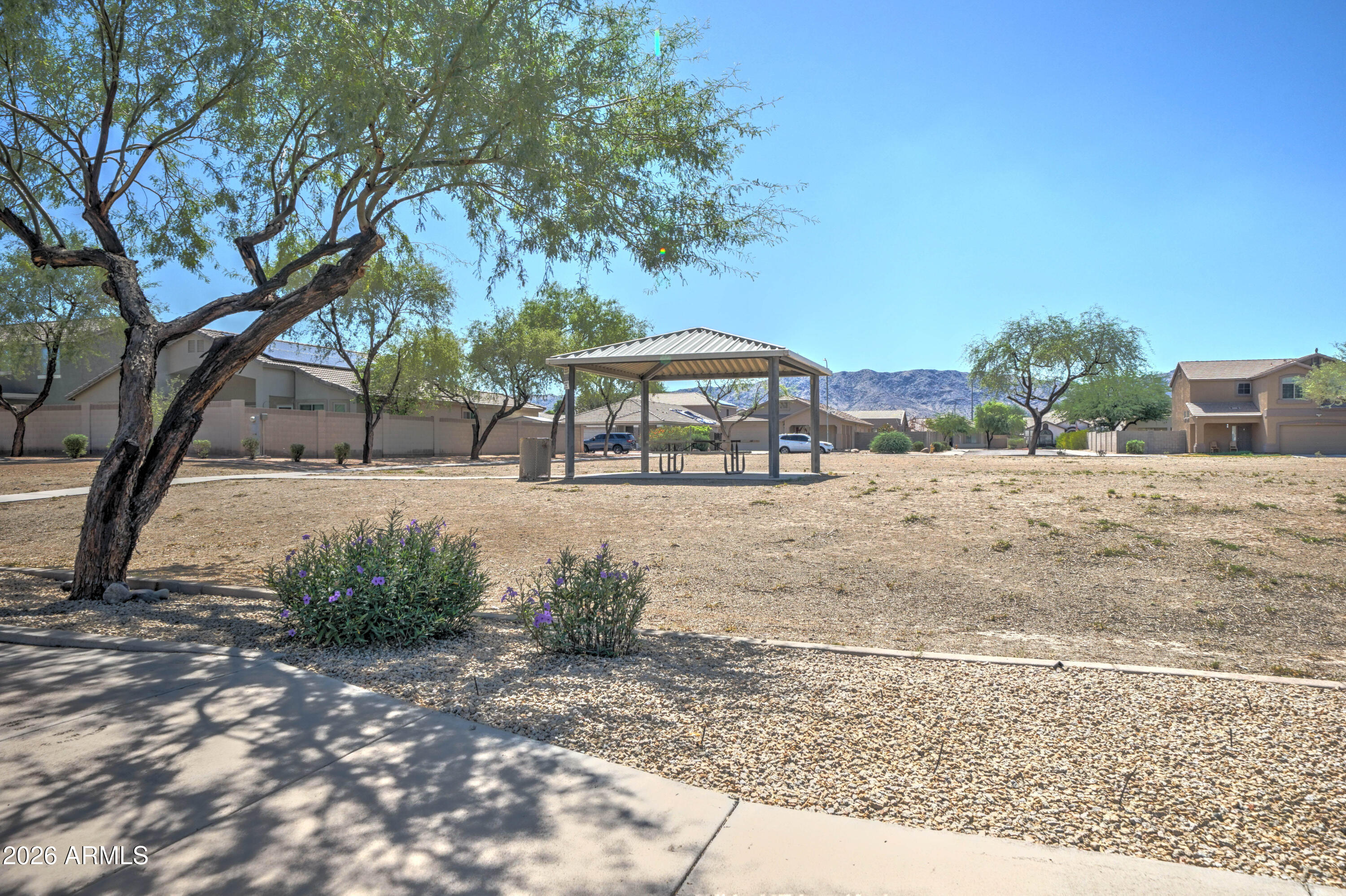 Neighborhood park with shaded picnic pavilion, desert landscaping, and mountains in the distance.