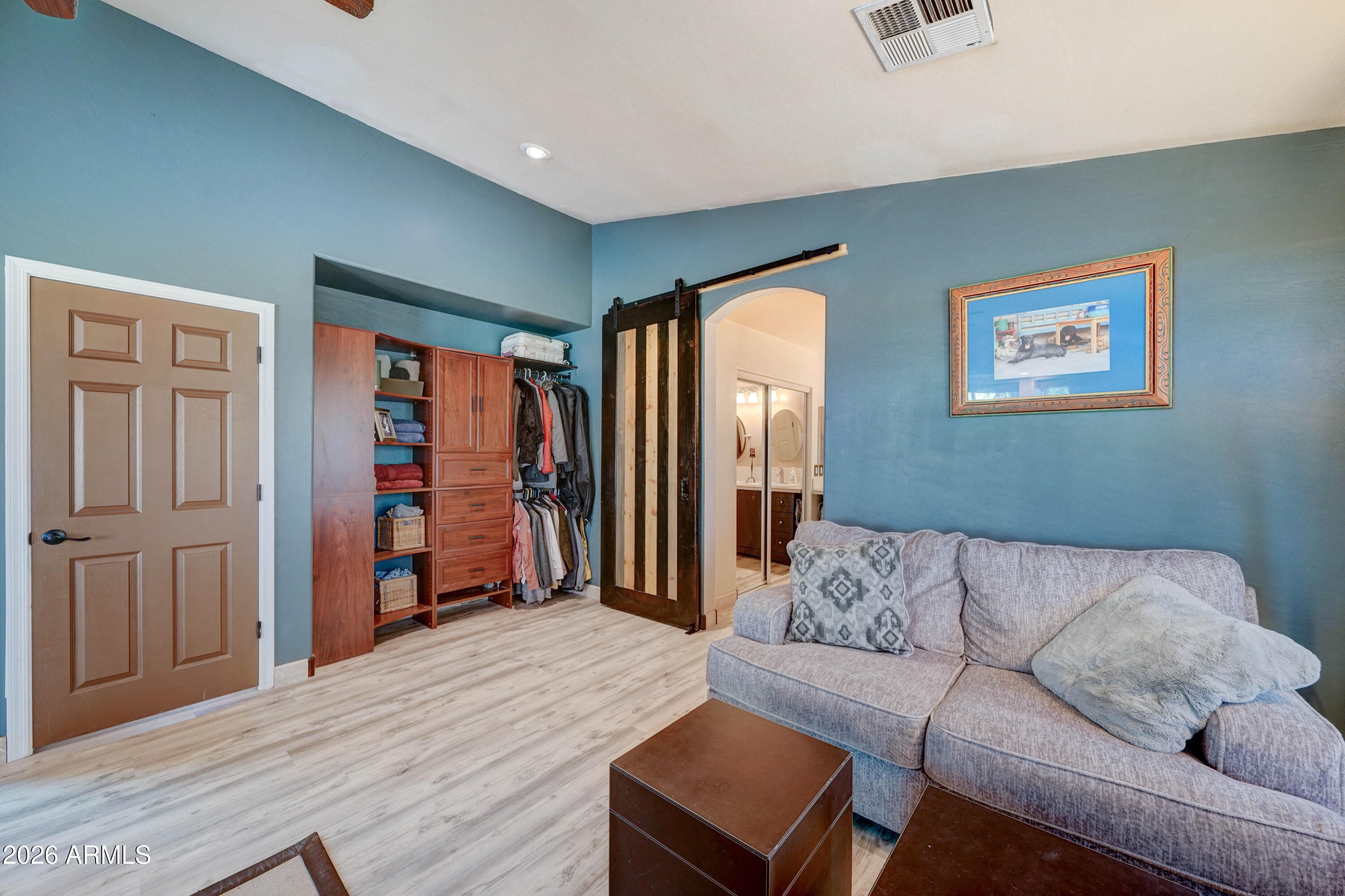 Blue sitting room with a gray sectional, built-in closet storage, and a sliding barn door.