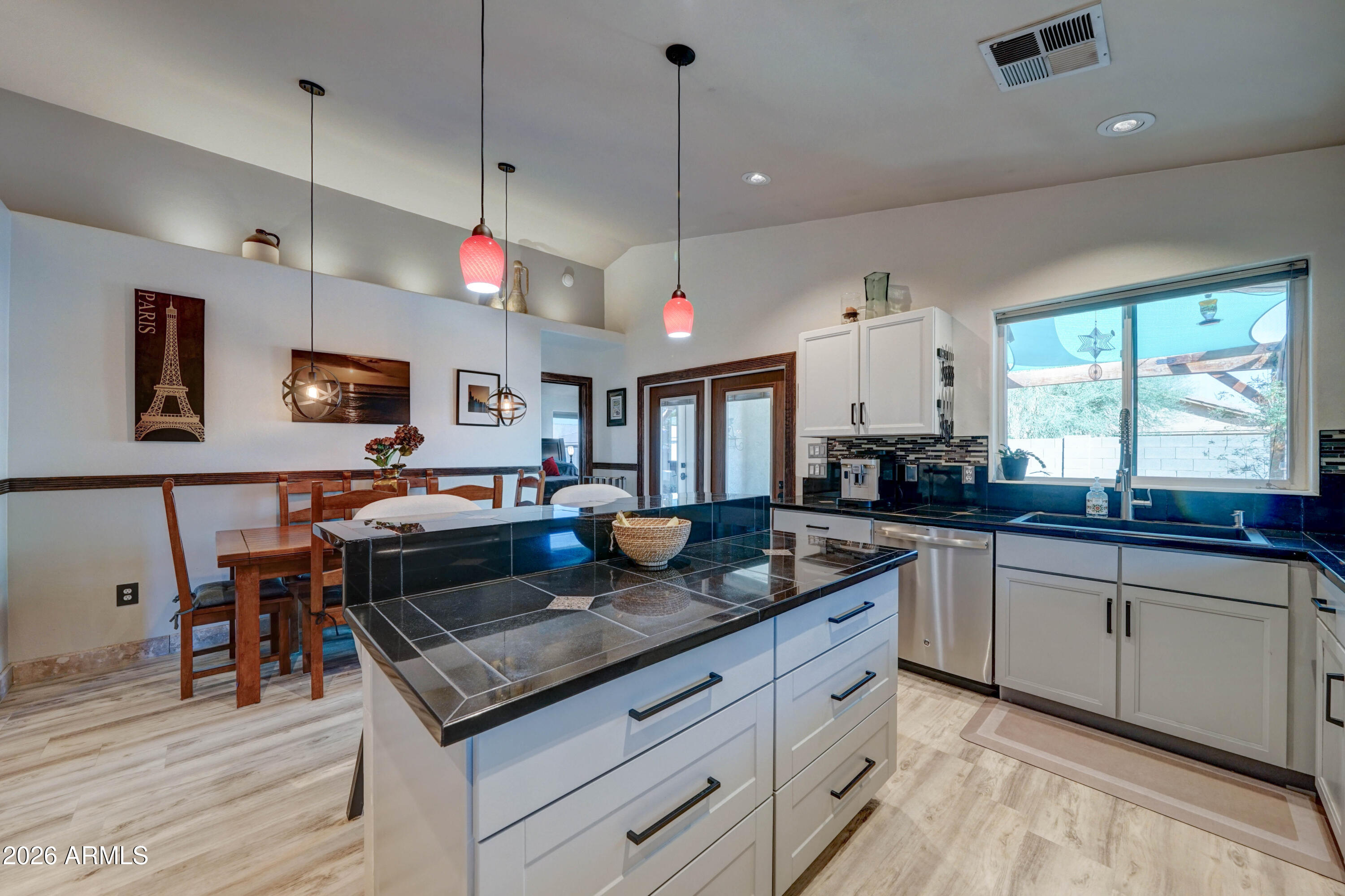 Kitchen with a dark tiled island, white cabinets, and a dining nook beside a large window.