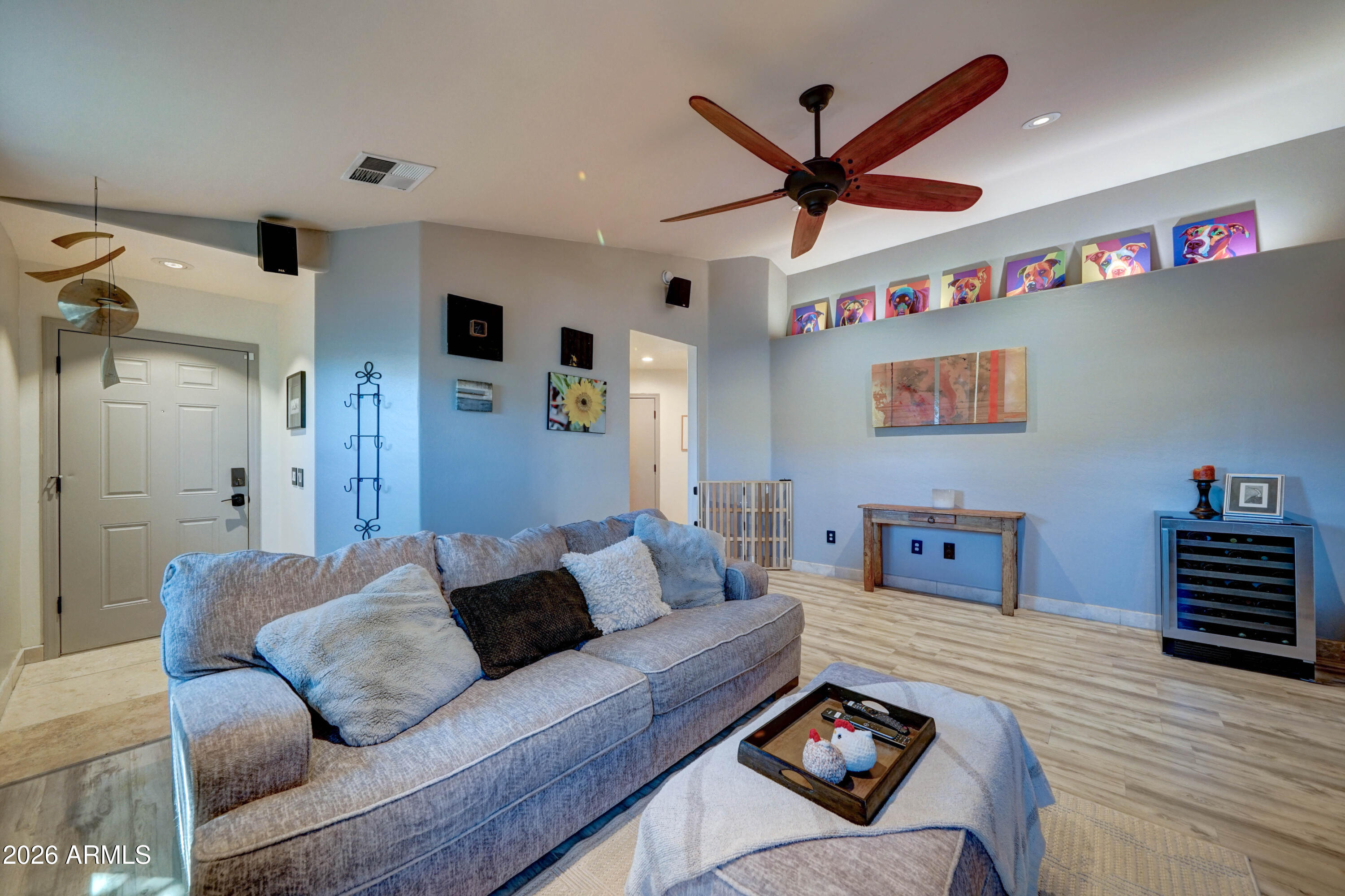 Furnished living room with a gray sectional sofa and colorful dog portraits above a console table.