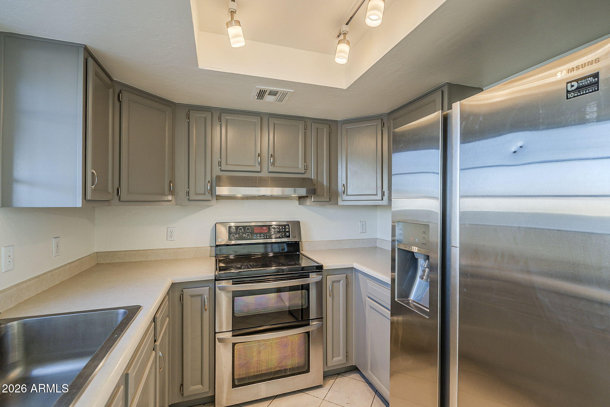 Kitchen with gray cabinets, stainless steel appliances, a double oven, and a large refrigerator.