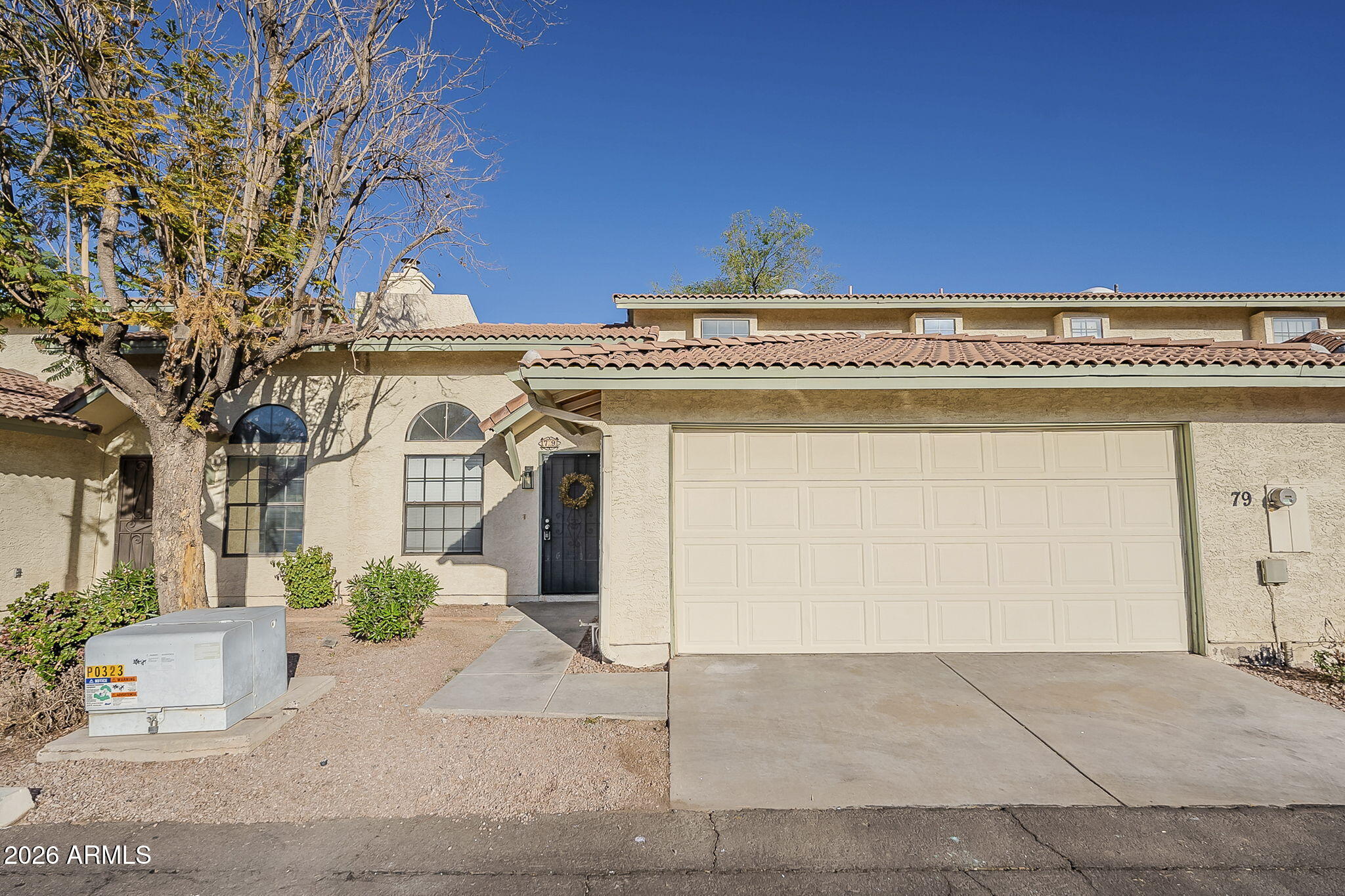 Stucco home with a tile roof, arched windows, and a large two-car garage.