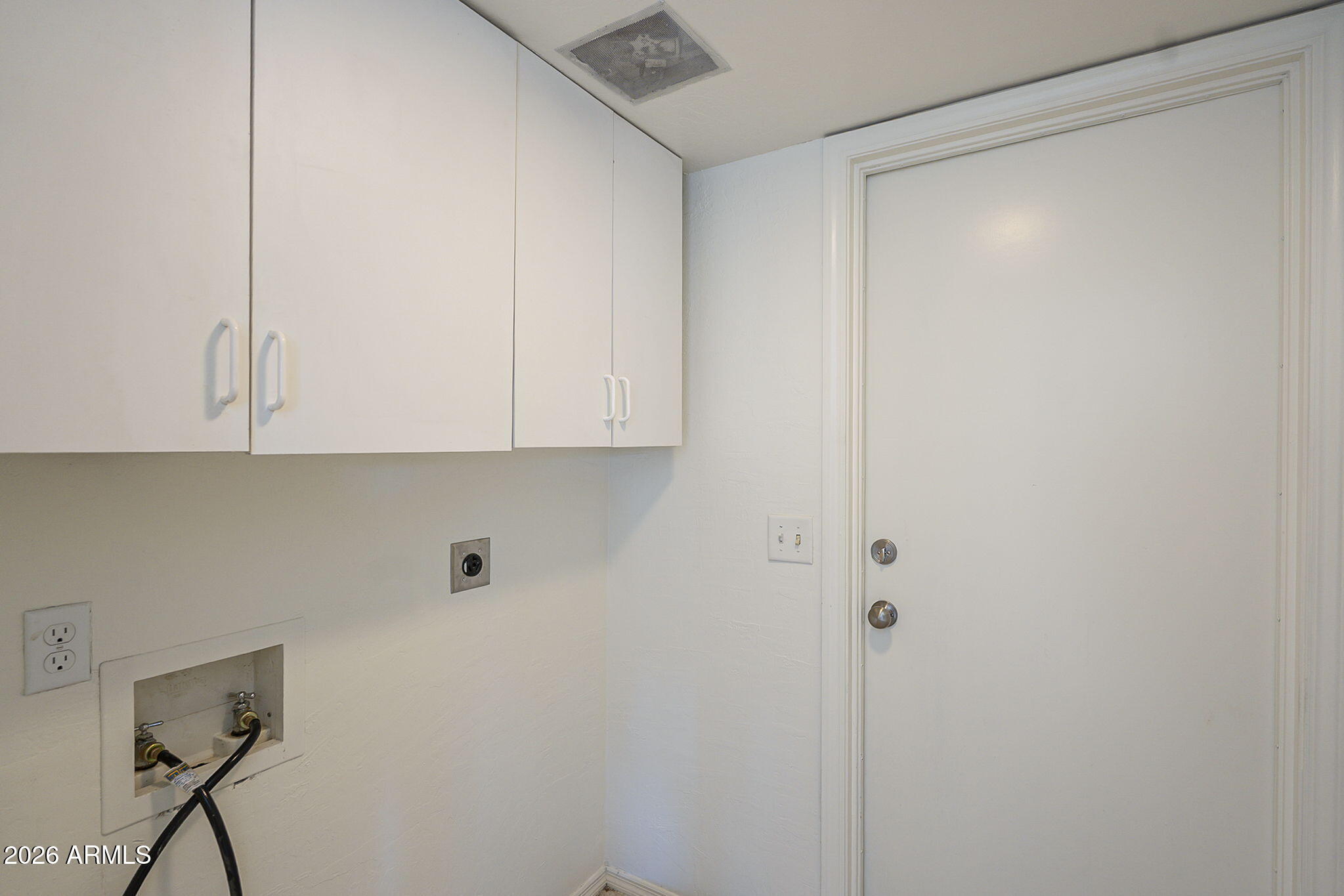 Laundry area with white cabinets, washer and dryer hookups, and a closed door.