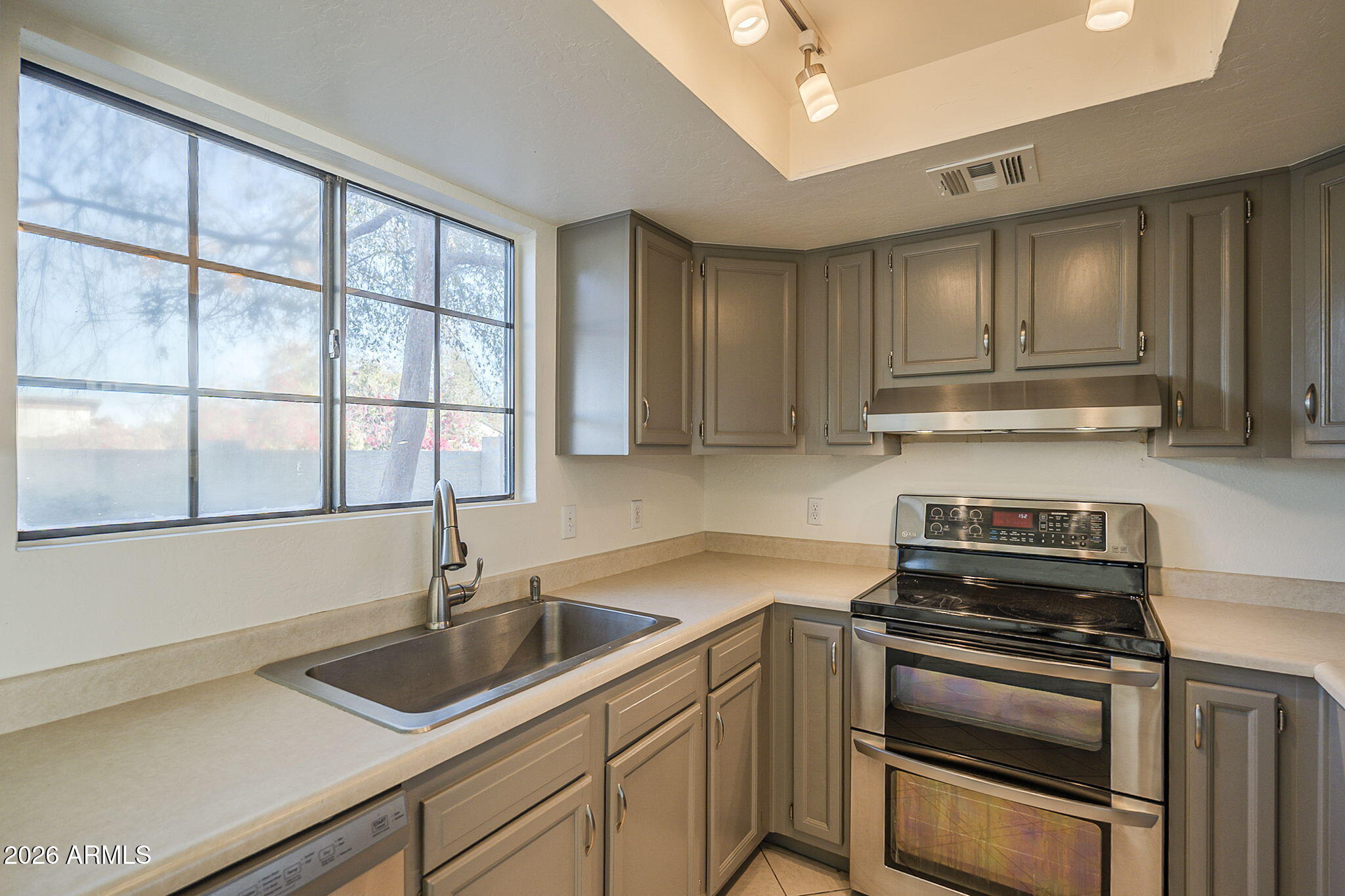 Kitchen with gray cabinets, a stainless steel double oven, and a large window over the sink.