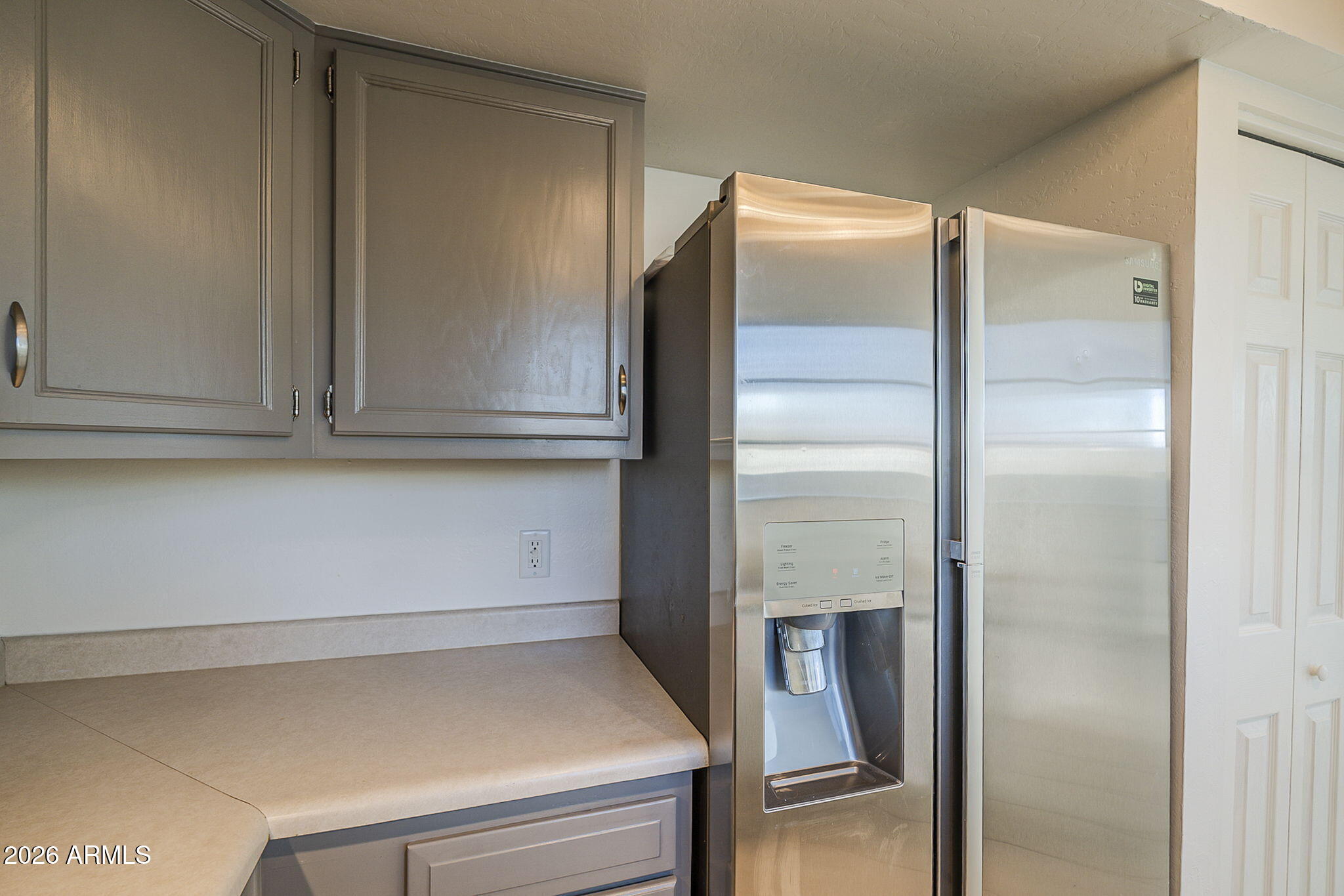 Kitchen with gray cabinets, a light countertop, and a stainless steel refrigerator with water and ice dispenser.