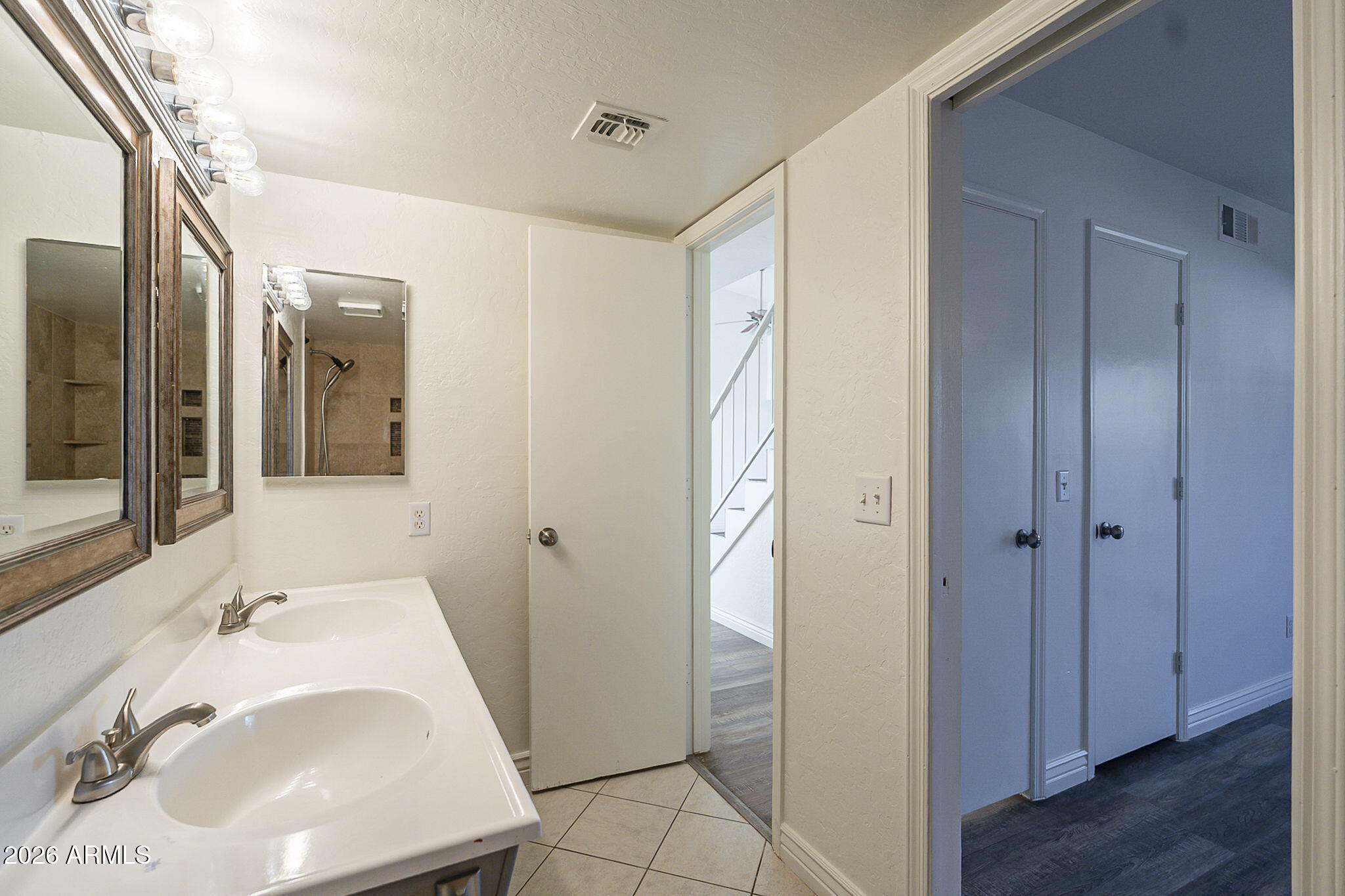 Bathroom with a double-sink vanity, framed mirrors, and an open doorway to a hall.