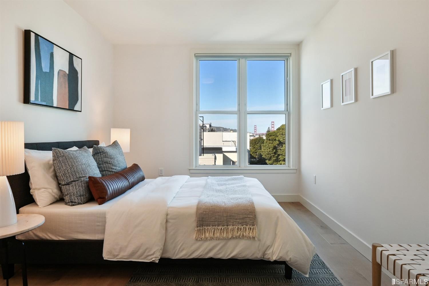 Staged bedroom with a neatly made bed and a window view of the Golden Gate Bridge.