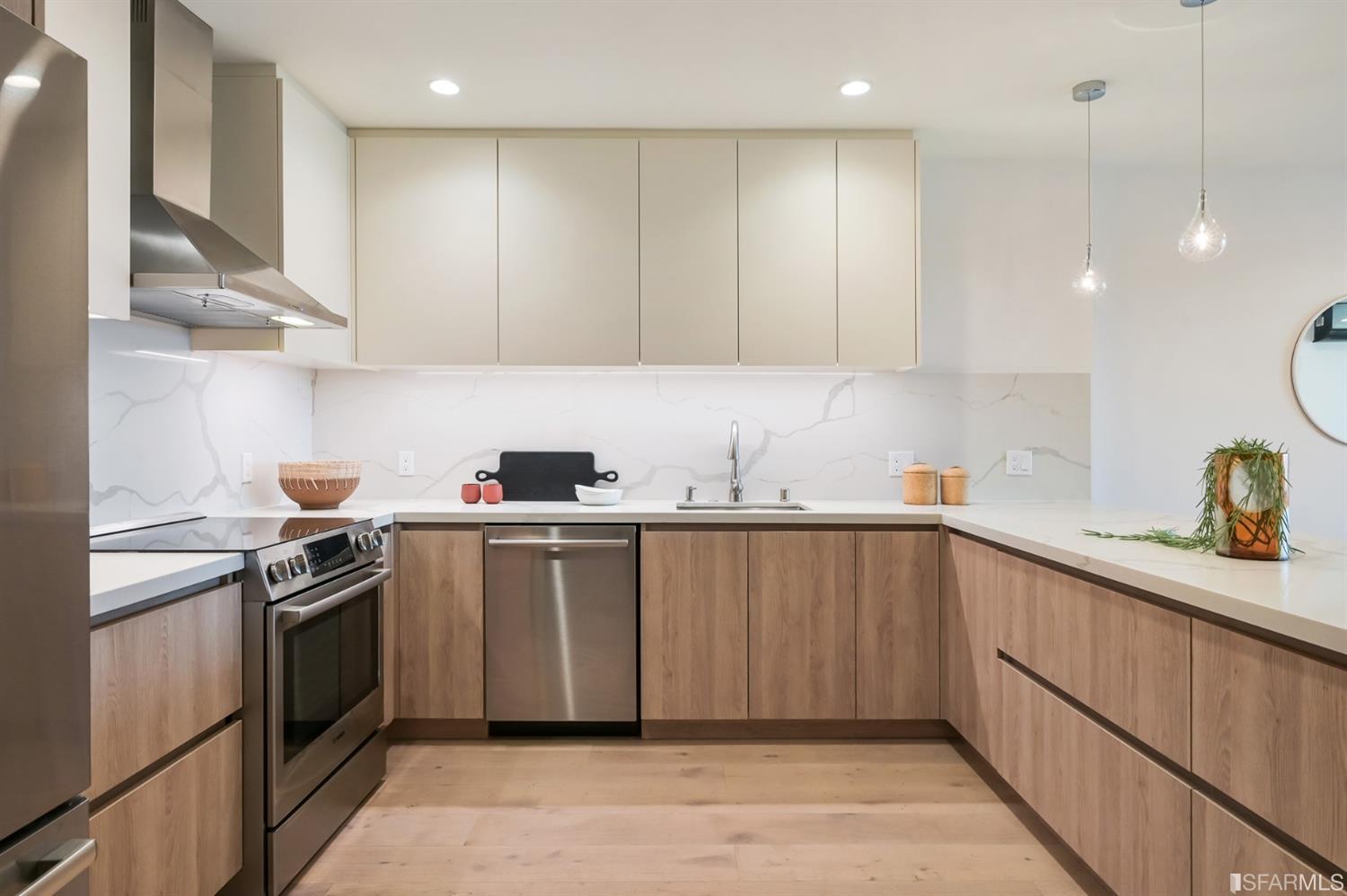 Modern kitchen with wood cabinets, marble-look counters, and stainless steel appliances.