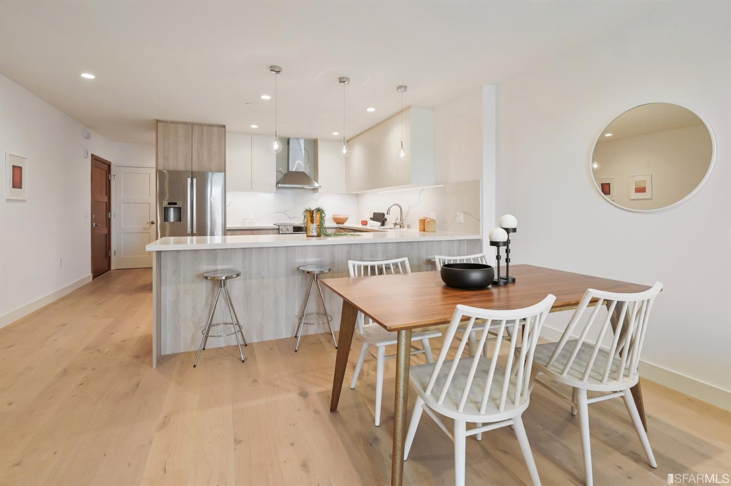 Open-plan kitchen with a large island and dining area furnished with a wood table and white chairs.