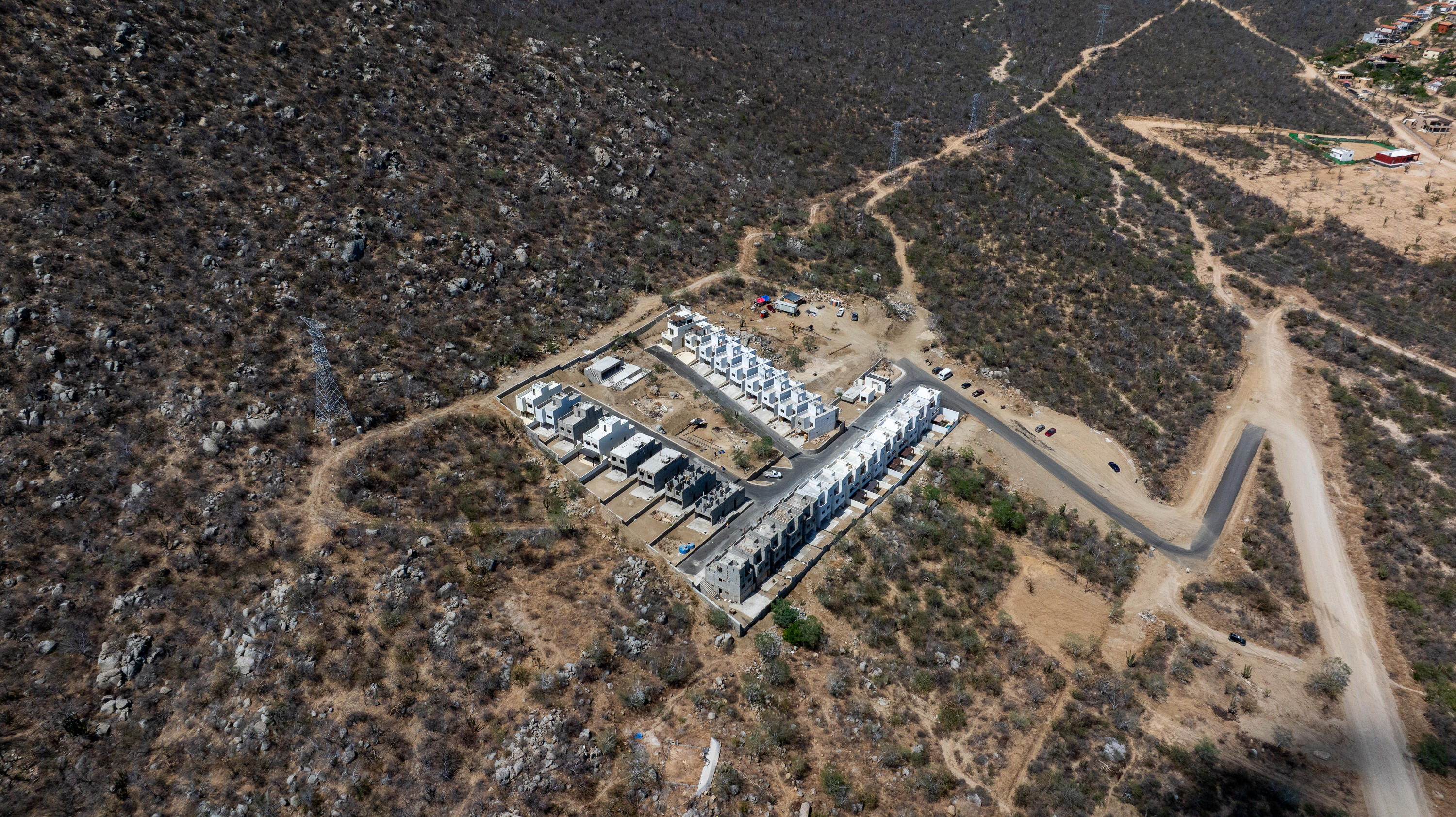 Aerial view of a housing development under construction amid rocky, arid hills.