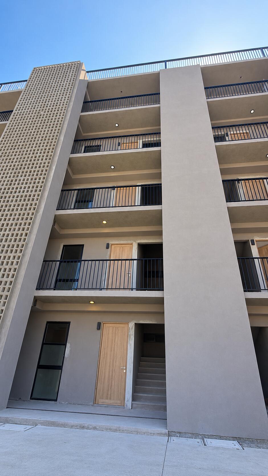 Monte Rocella’s modern facade with stacked balconies, dark railings, and a perforated concrete screen.
