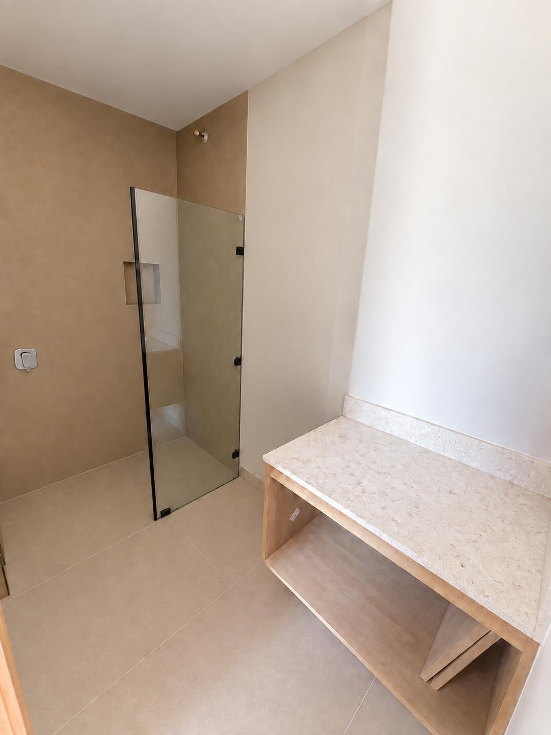 Bathroom with a frameless glass shower and pale stone vanity countertop.
