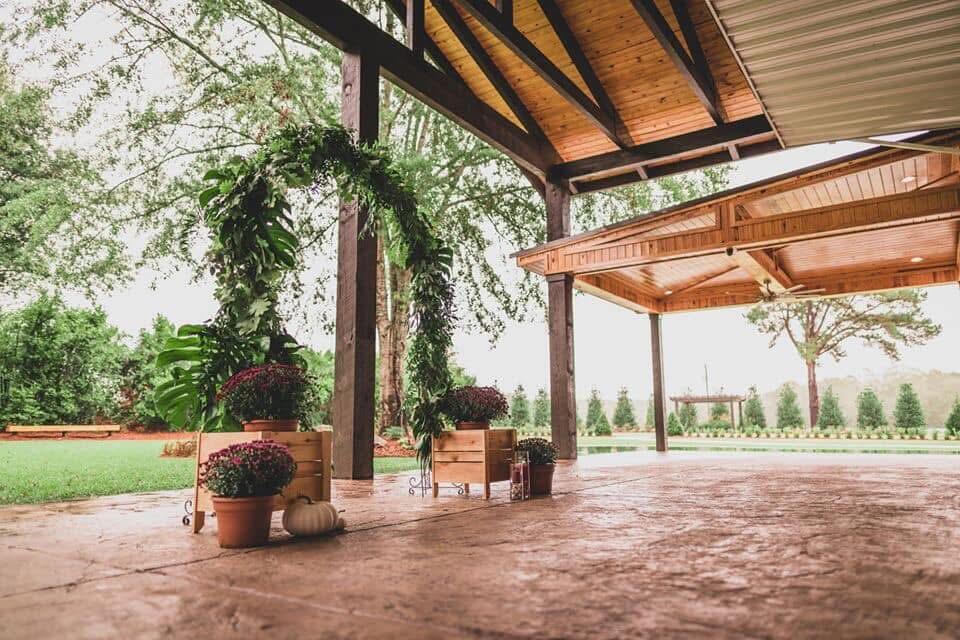 Covered timber patio with brick flooring, potted plants, and a landscaped lawn.