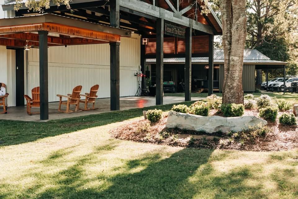 Building exterior with a covered timber patio, rocking chairs, and landscaped lawn.