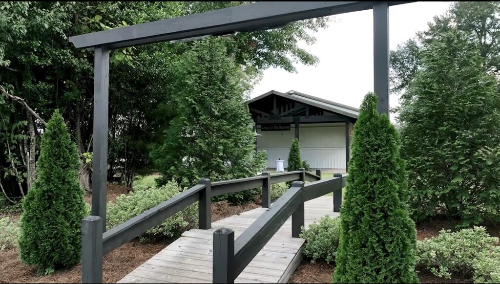 Landscaped walkway with dark railings leading to a small white building.