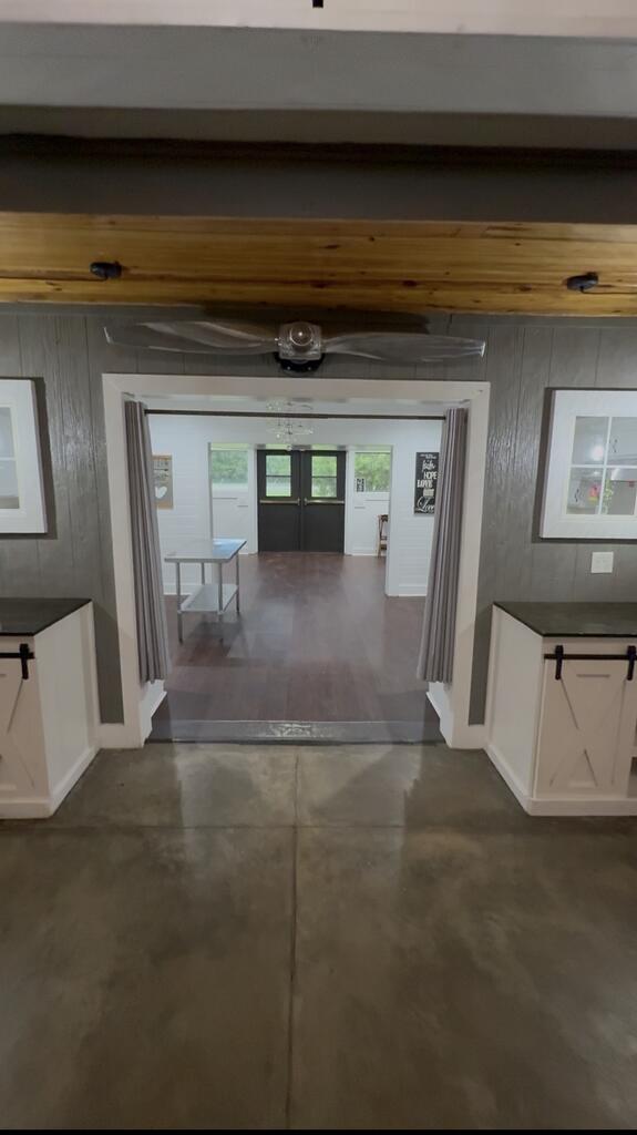 Kitchen opening into a bright room with dark double doors, a table, and wood-look flooring.