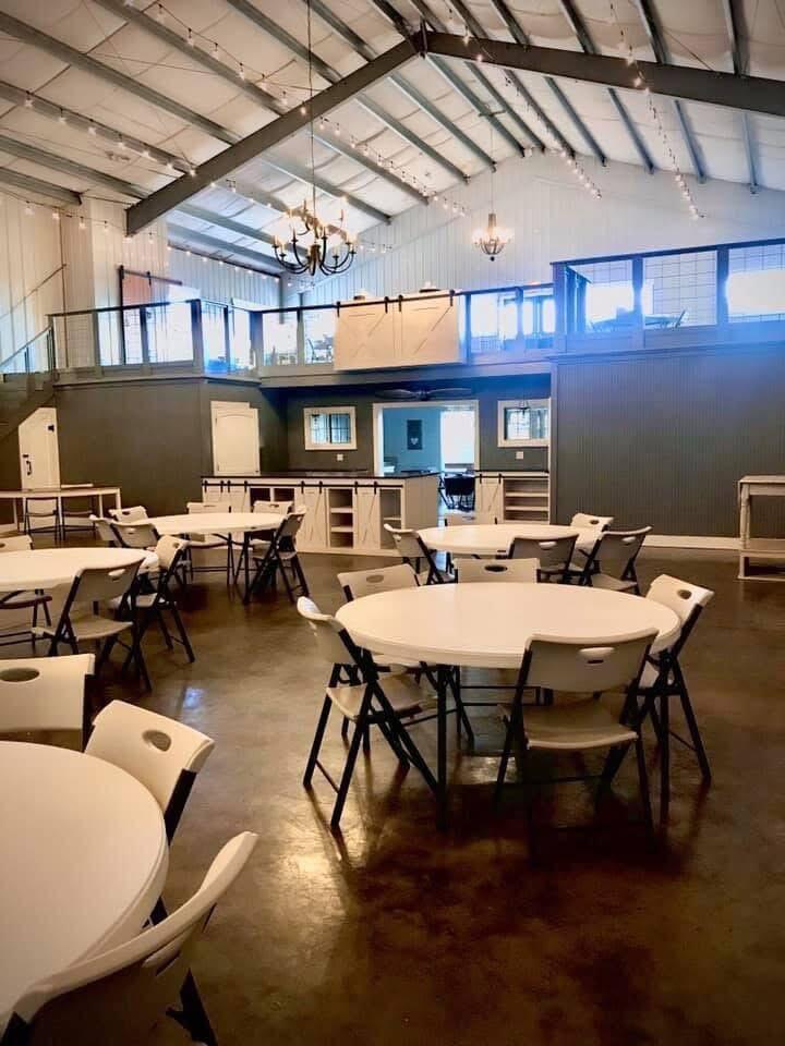 Large event hall with round tables, folding chairs, and a mezzanine.