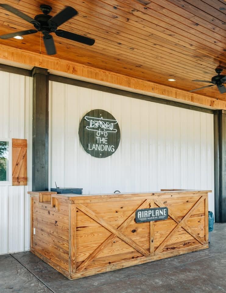 Reception counter at The Landing, with a wooden ceiling, ceiling fans, and an Airplane Hangar sign.