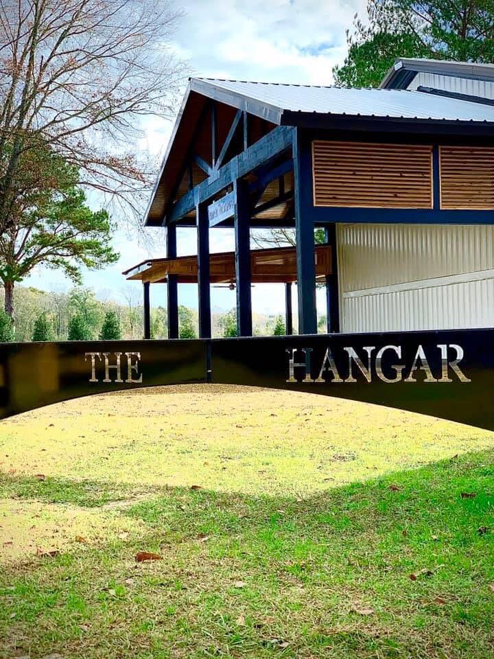 Hangar-style building with blue beams and a curved sign reading “THE HANGAR.”
