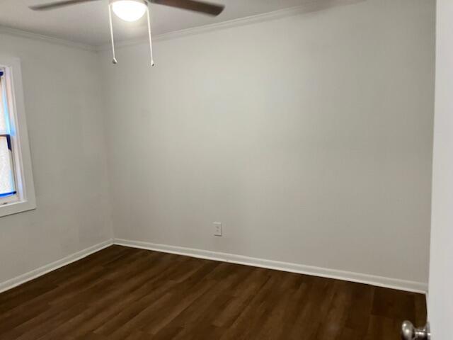 Empty room with dark wood-look flooring, a window, and a ceiling fan with light.