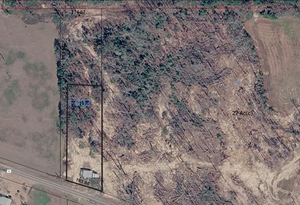 Aerial view of a 27-acre wooded parcel outlined beside a road.