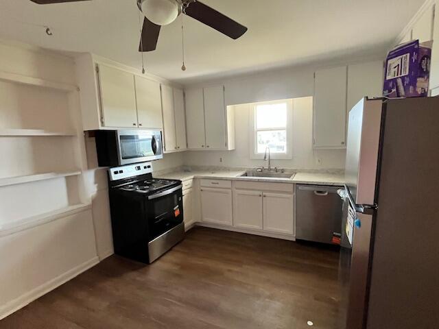 Kitchen with white cabinets, black range and microwave, and a window above the sink.