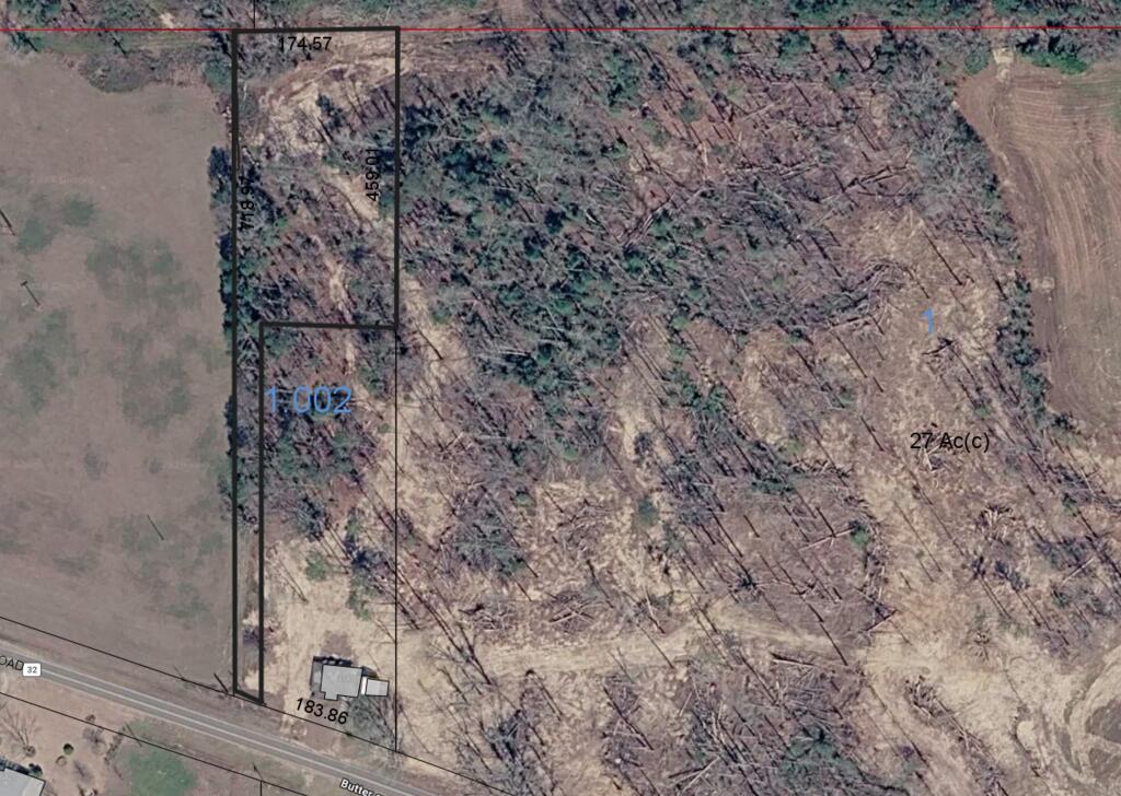 Aerial view of wooded acreage outlined along a paved road, with neighboring fields and parcel measurements.
