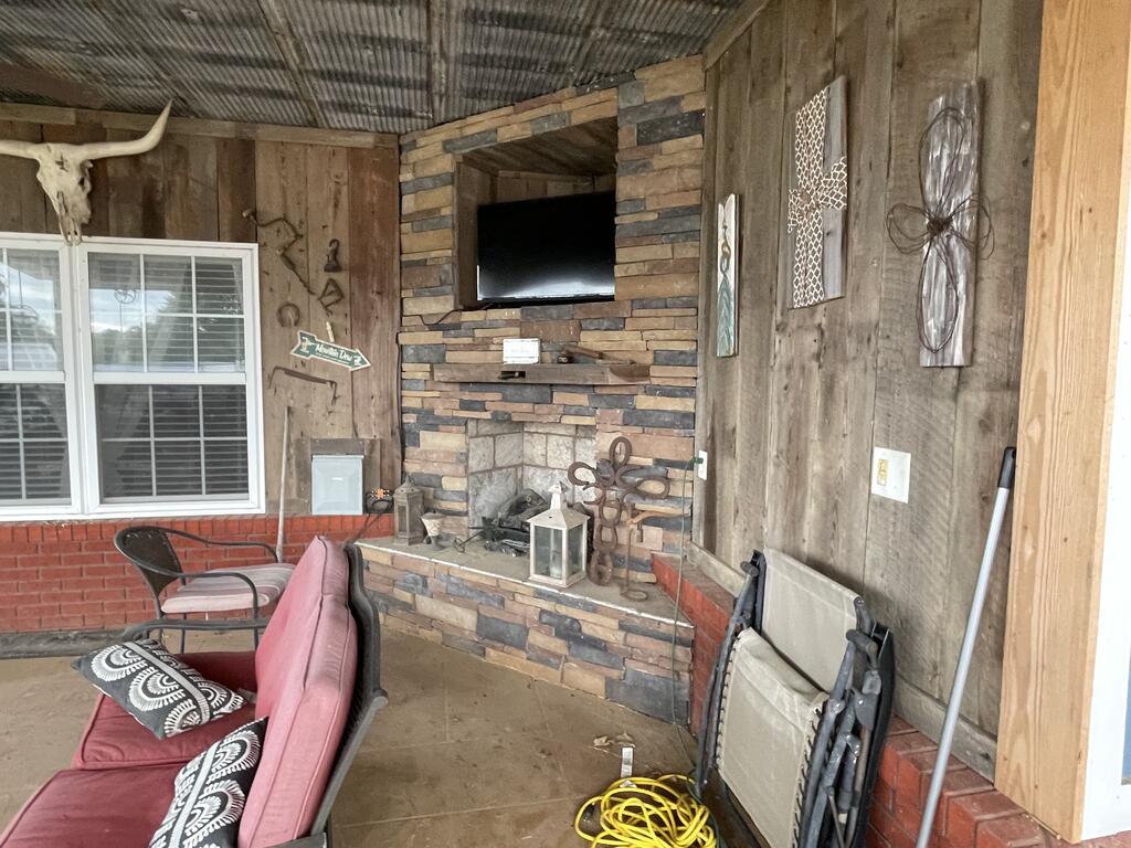 Rustic sitting area with a stone fireplace, mounted television, and cushioned seating.
