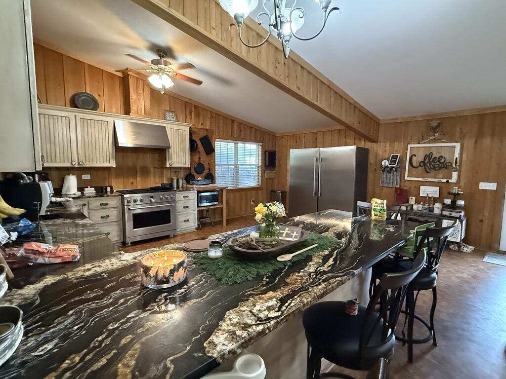 Kitchen with a large veined stone island, bar seating, and wood-paneled walls.