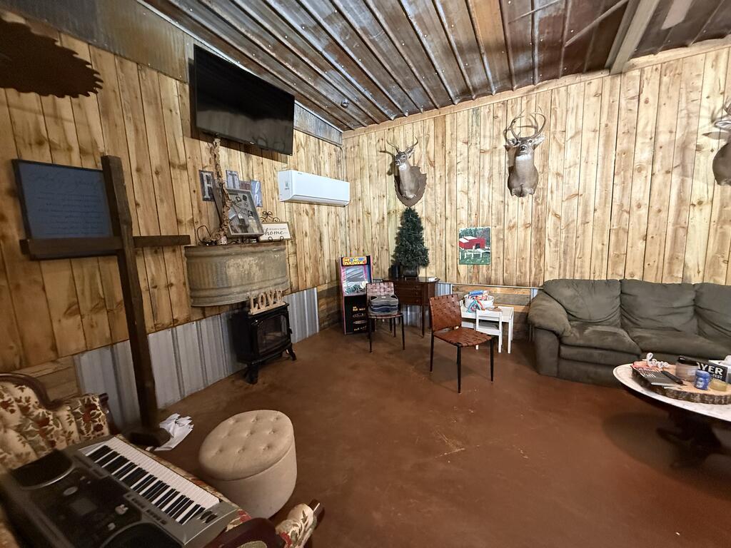 Rustic wood-paneled living room with mounted deer heads, a wood stove, and gray sofa.