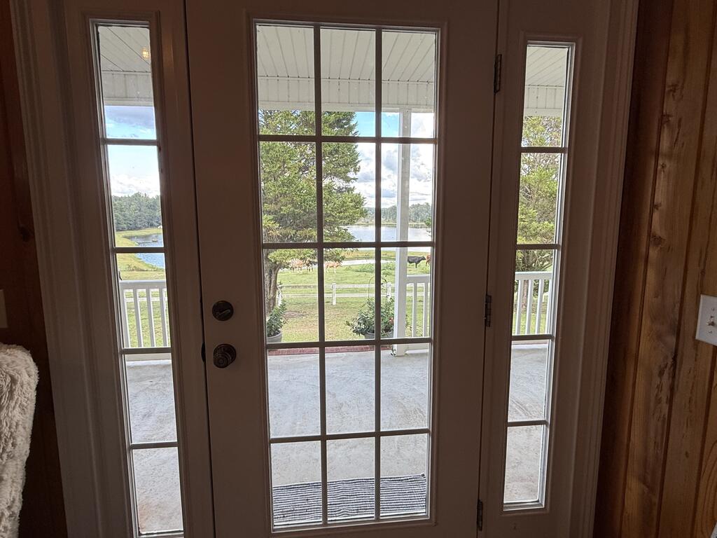 Glass-paneled door overlooking a porch, green lawn, and lake.