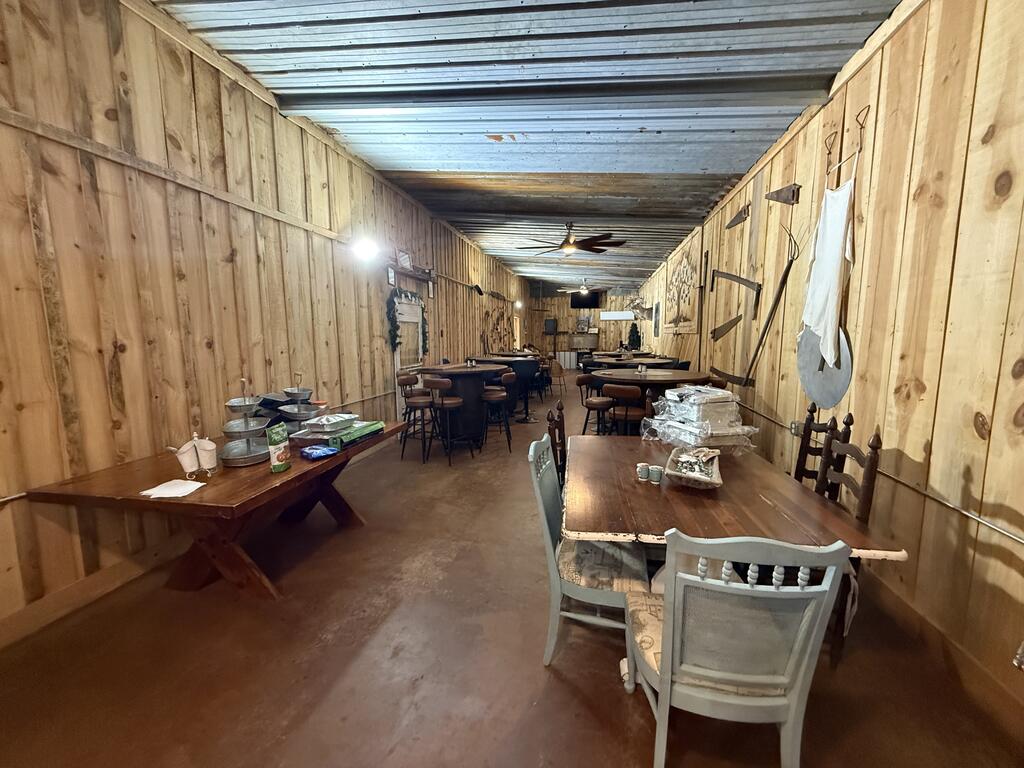 Long wood-paneled dining room with tables, chairs, serving dishes, and a ceiling fan.