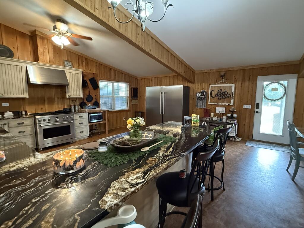 Kitchen with a dramatic veined stone island, wood-paneled walls, and stainless steel appliances.
