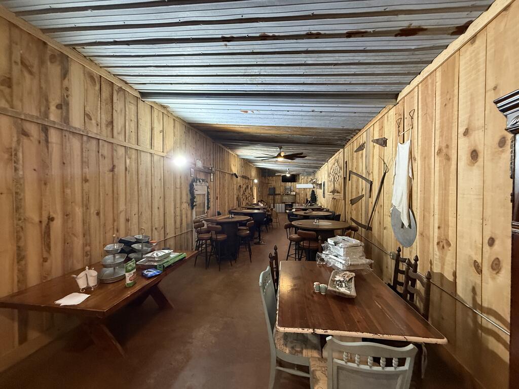 Rustic dining room with wood-paneled walls, rows of tables, and serving dishes.