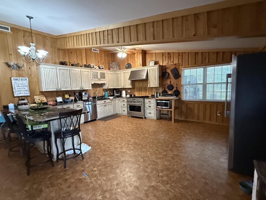 Spacious wood-paneled kitchen with white cabinets, stainless appliances, and a dining table.
