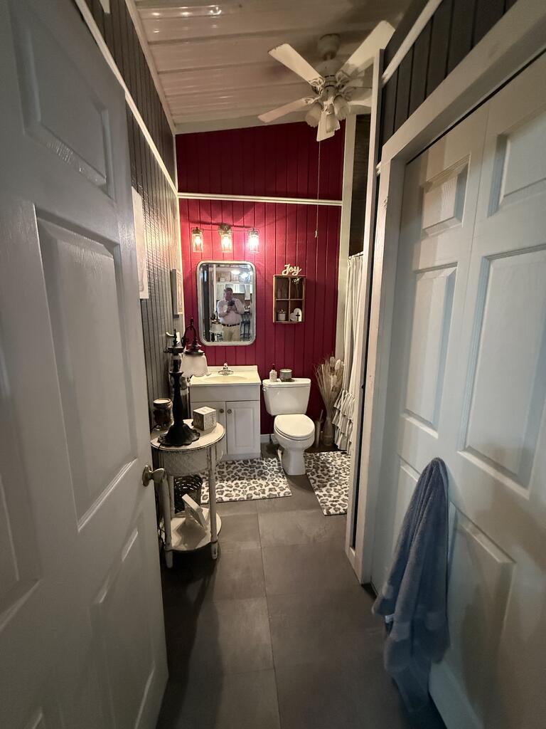 Bathroom with a red paneled accent wall, white vanity and toilet, and gray tile floor.