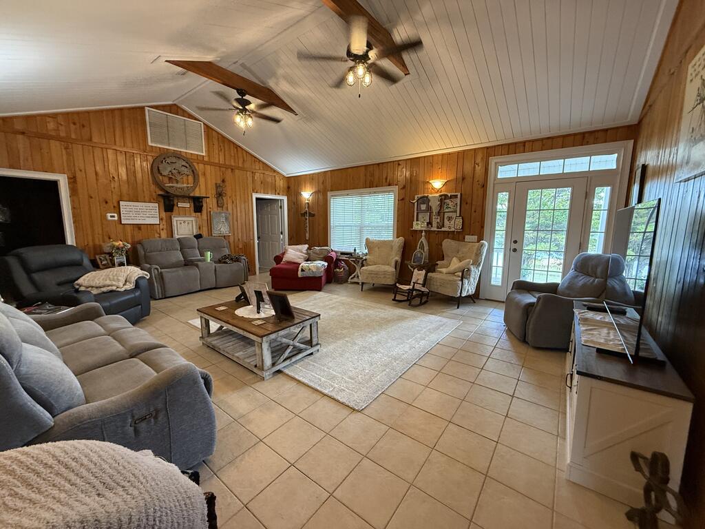 Furnished living room with wood-paneled walls, vaulted ceiling, and glass doors.