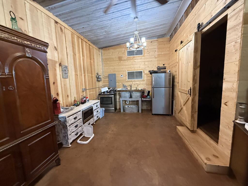 Rustic wood-paneled kitchen with a refrigerator, stove, and sink.