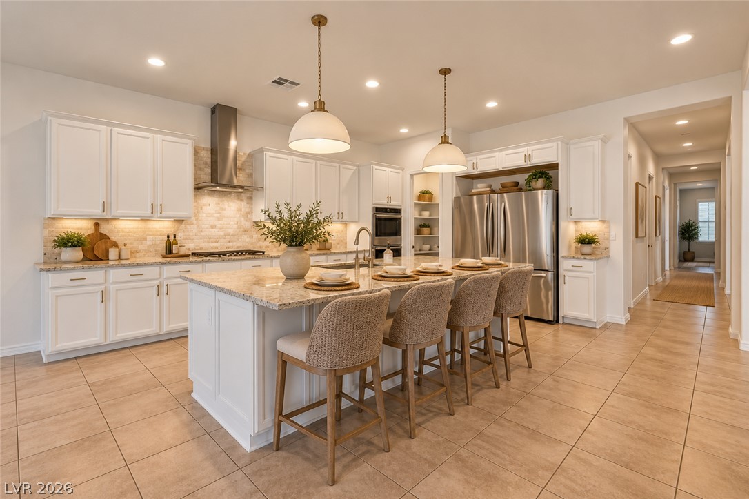 Staged kitchen with a granite island, four bar stools, white cabinets, and stainless steel appliances.