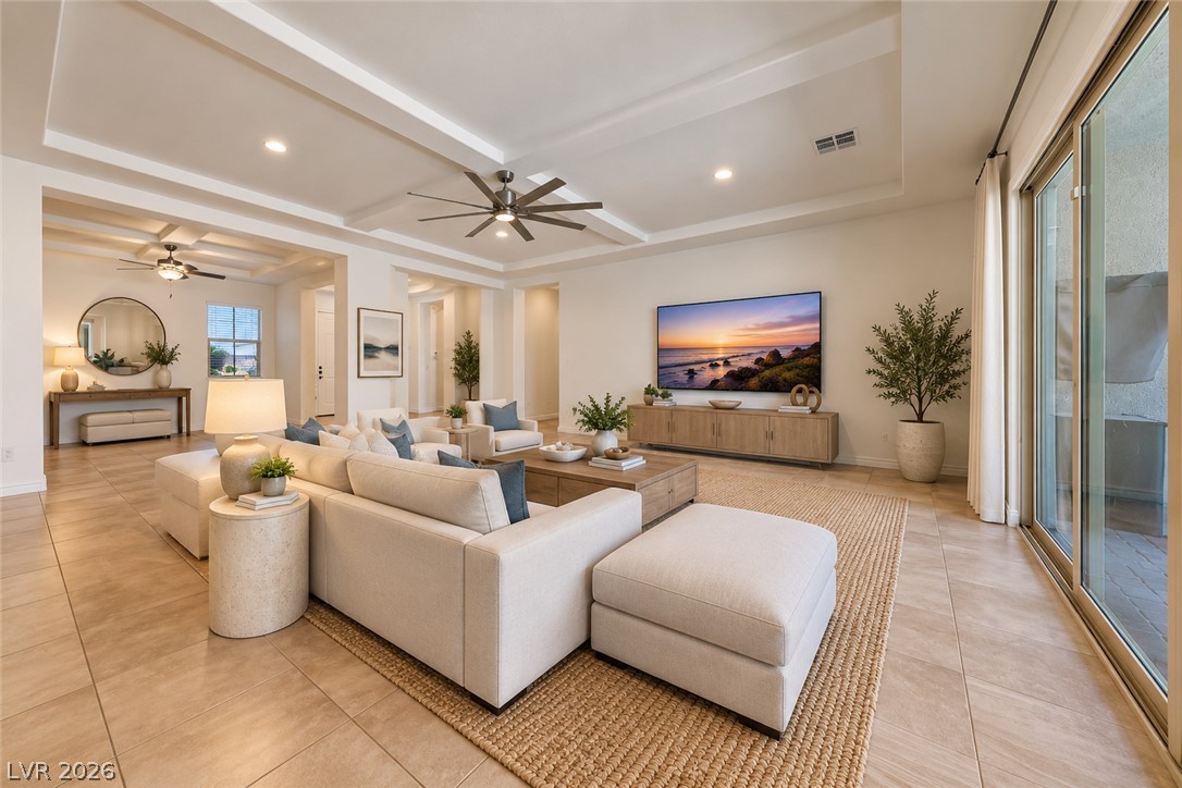 Staged living room with a white sectional, coffered ceiling, and large sliding glass doors.