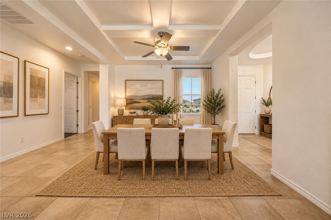 Dining room with a wooden table, upholstered chairs, woven rug, and coffered ceiling.